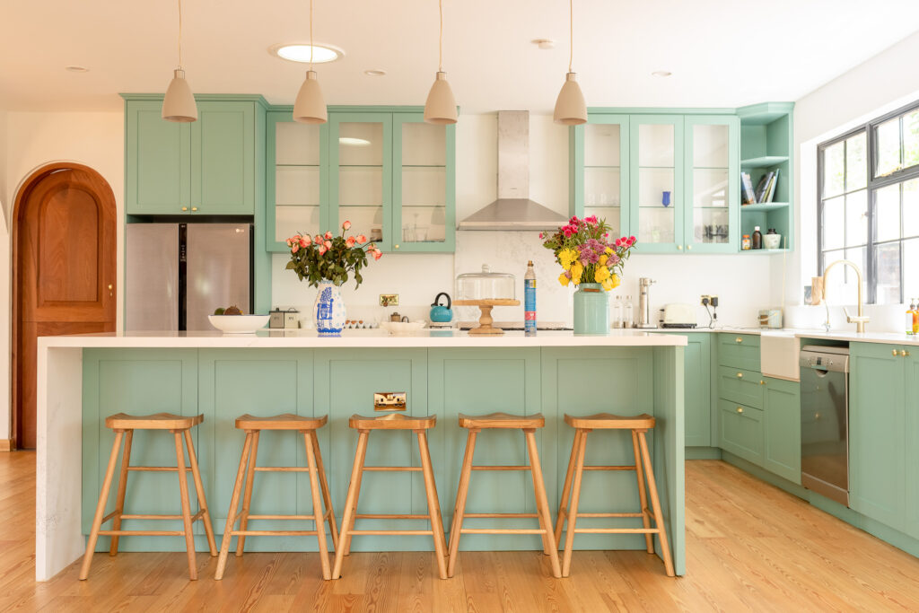 Mint green fitted kitchen with an island and bar stools