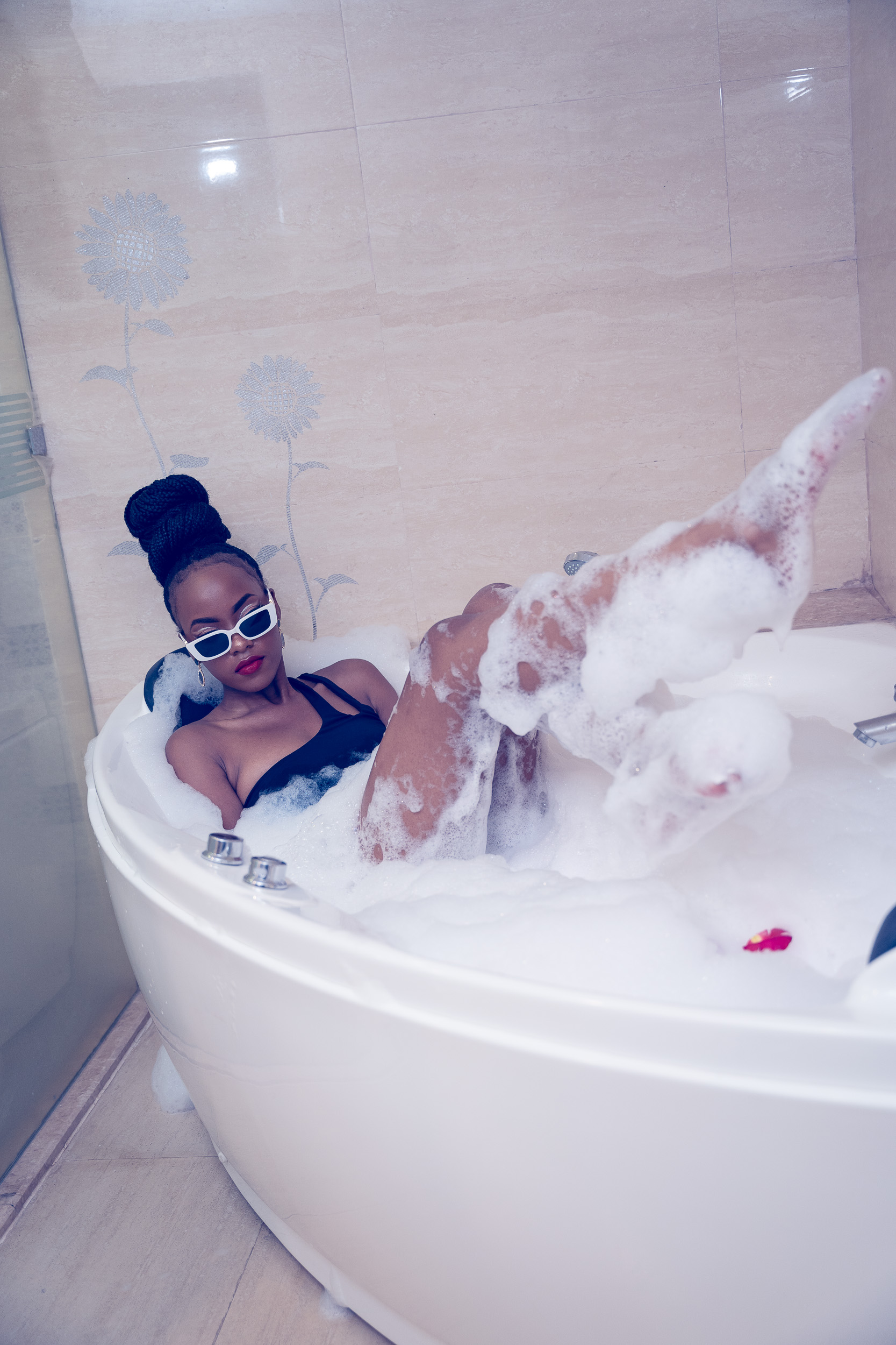 Portrait of a woman wearing sunglasses relaxing in a bubble bath