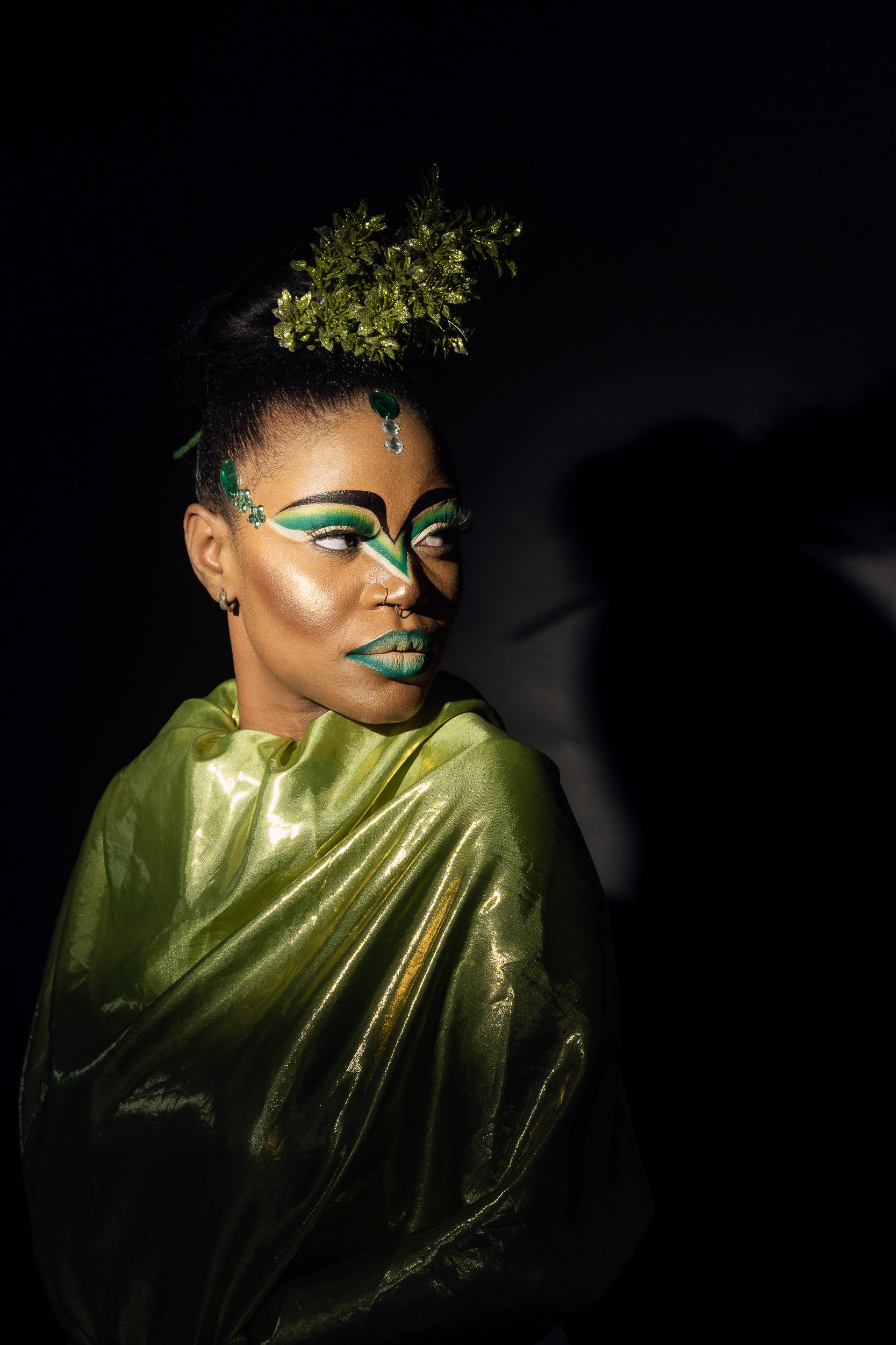 Creative beauty portrait of a woman in a green metallic wrap with graphic green eye makeup