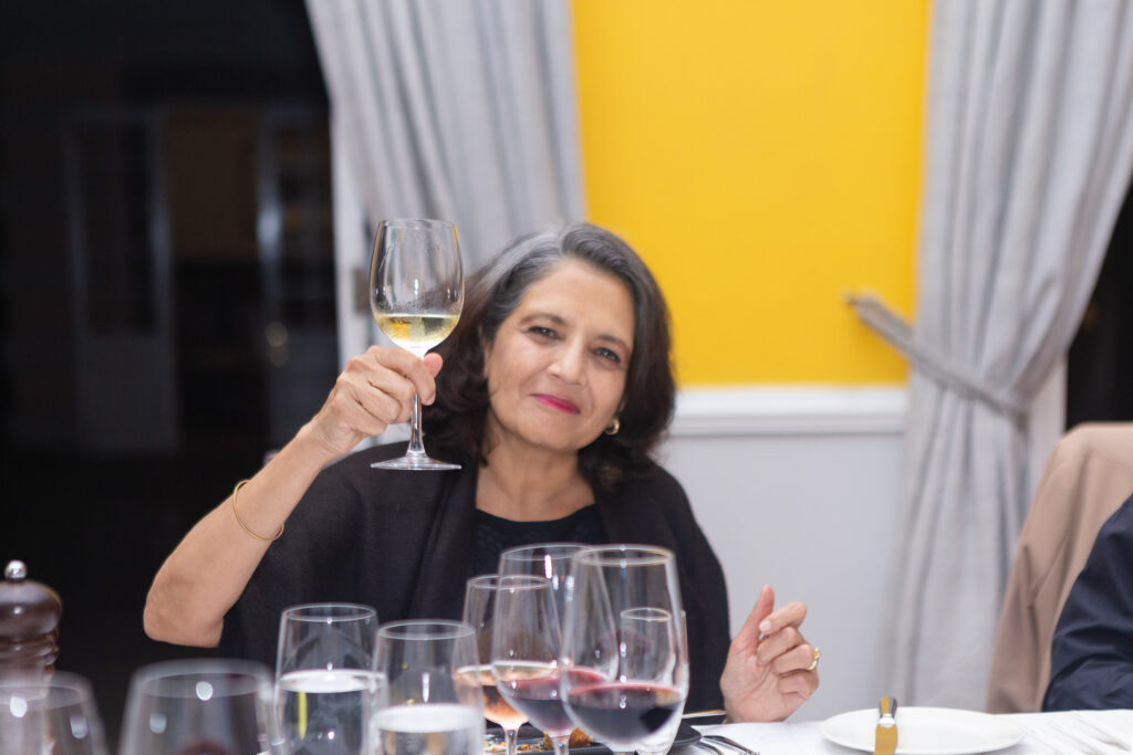 Guest laughing with a glass of white wine at a formal dinner
