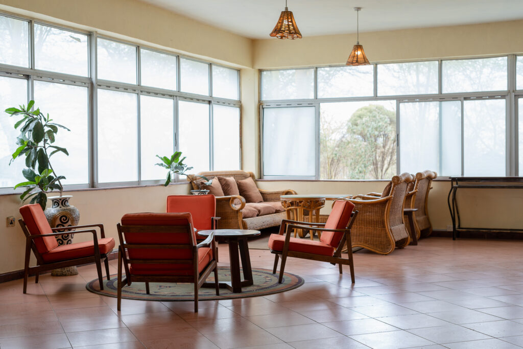 Sunlit lounge with red armchairs and large windows