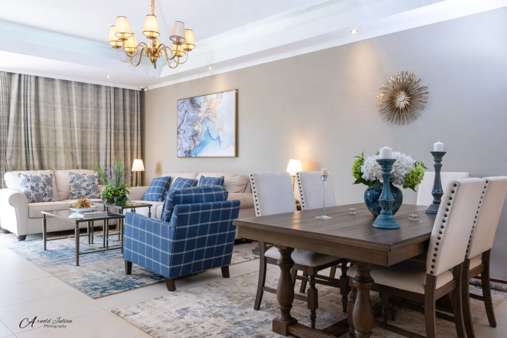 Open plan living and dining room with blue armchairs and a chandelier