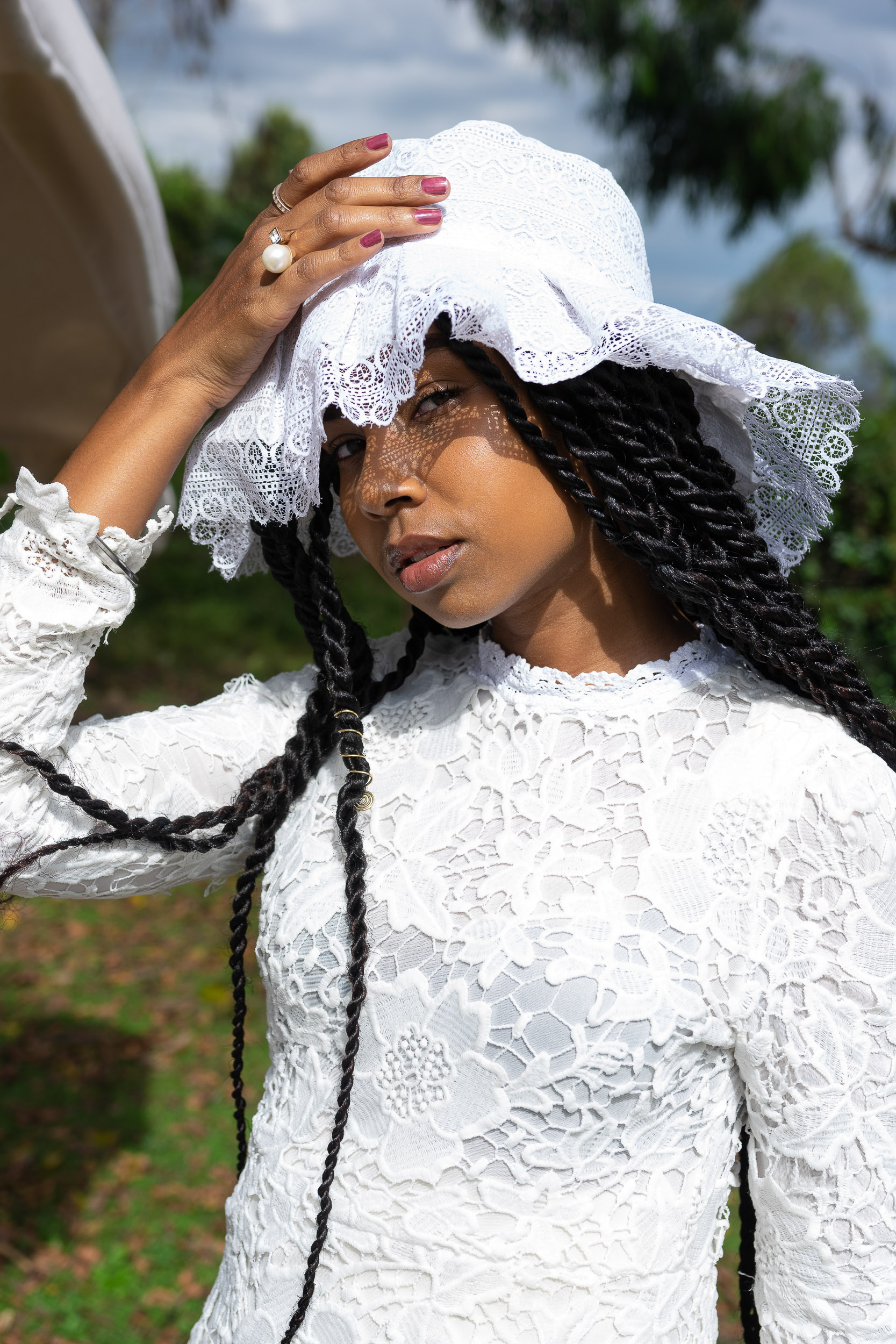 Outdoor portrait of a woman in a white lace dress and matching bonnet