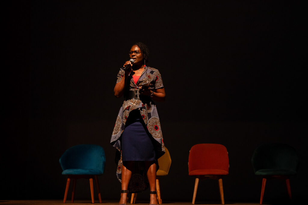 Speaker addressing an audience from a darkened stage