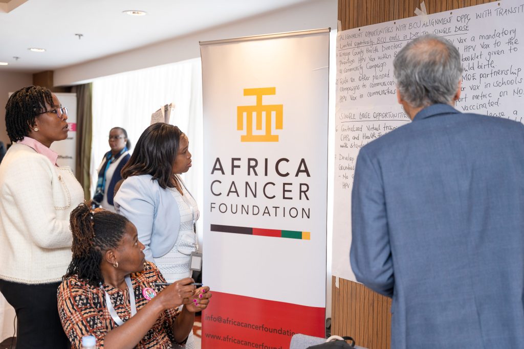 Attendees networking beside an Africa Cancer Foundation banner