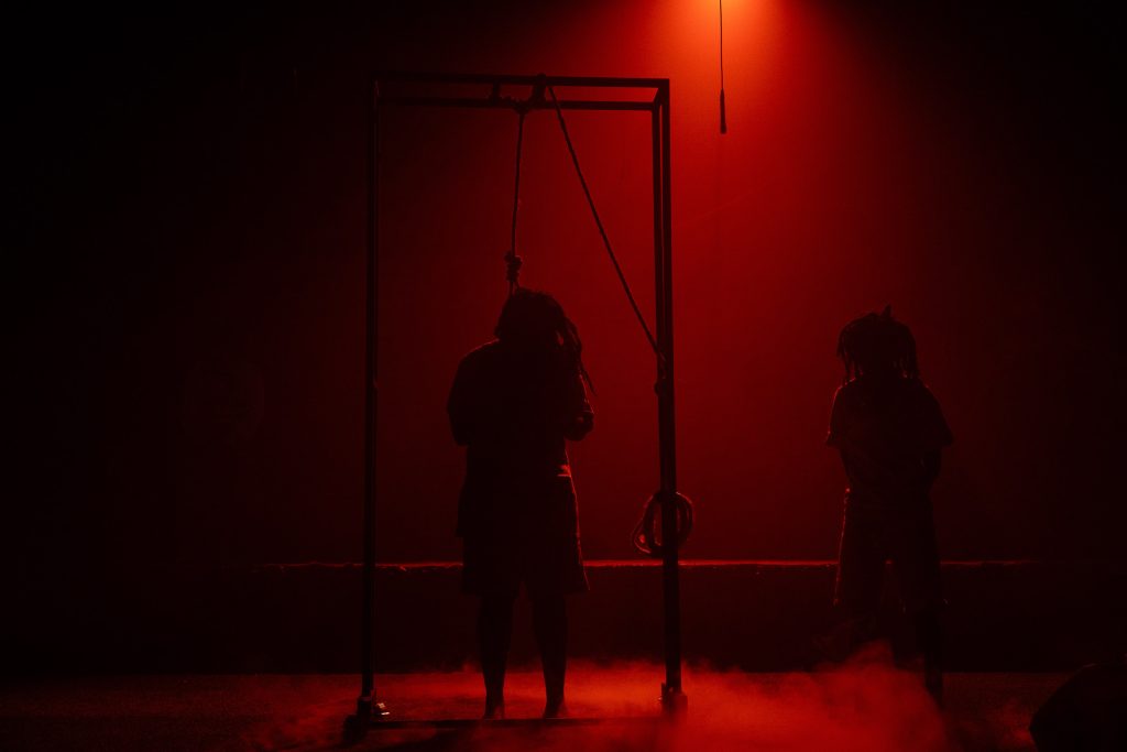 Performers silhouetted on stage under deep red lighting