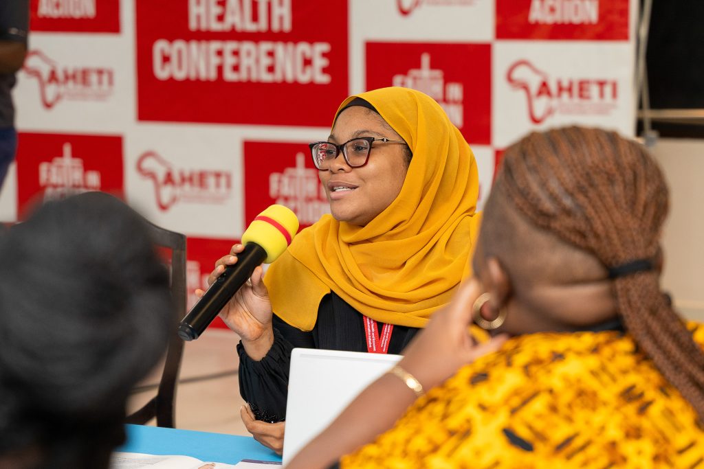 Speaker in a yellow hijab addressing a health conference